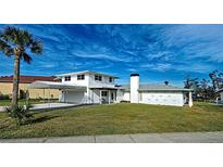 Bright two-story home featuring a two-car garage with attached covered parking and a well-manicured front lawn at 202 South Dr, Englewood, FL 34223