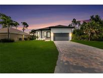 Beautiful single-Gathering home featuring a manicured lawn and brick paver driveway under a gorgeous sunset sky at 280 Antis Dr, Rotonda West, FL 33947