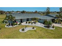 Well-maintained home with a landscaped front yard, gray roof, manicured lawn, and fresh exterior paint at 62 Oakland Hills Pl, Rotonda West, FL 33947