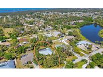 A picturesque aerial view shows the home with pool, lush greenery and water views in a coastal community at 850 Van Gogh Road, Englewood, FL 34223