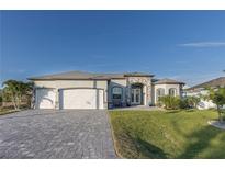 Stunning home with a stone archway entrance, three-car garage, and patterned brick driveway at 9214 Melody Cir, Port Charlotte, FL 33981