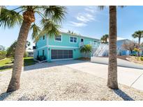 Exterior shot of a home with a 2-car garage and palm trees in the front yard with an all-stone lawn at 9230 Pine Cove Dr, Englewood, FL 34224