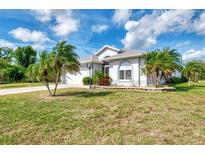 Well maintained single-story home with manicured lawn, landscaping, and palm trees at 115 Australian Dr, Rotonda West, FL 33947
