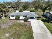 An elevated view showcasing a well-maintained white house, spacious driveway, and landscaped front yard at 1493 Kathleen Pl, Englewood, FL 34223