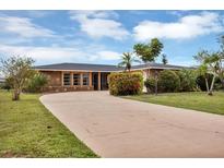 Charming single-story home with a stone facade, circular driveway, and lush landscaping at 18 Annapolis Ln, Rotonda West, FL 33947