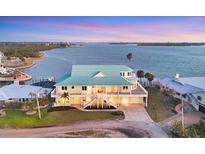 Stunning waterfront home with a teal roof, spacious balconies, and lush landscaping, offering breathtaking water views at 1905 Mississippi Ave, Englewood, FL 34224