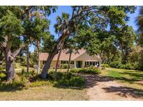 Charming yellow home surrounded by lush trees and landscaping, evoking a serene and inviting atmosphere at 2020 E Dolphin Dr, Englewood, FL 34223