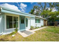 Inviting home front entrance with awning, blue door and trim, surrounded by lush landscaping and a clear walkway at 221 Nippino E Trl, Nokomis, FL 34275