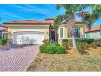 Charming single-story home with red tile roof, paver driveway, and meticulously manicured landscaping at 24181 Gallberry Dr, Venice, FL 34293