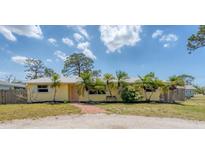 Charming yellow home featuring a brick walkway and beautifully landscaped front yard with mature palm trees at 551 Morrison Ave, Englewood, FL 34223