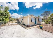 Charming single-story home featuring a gravel yard, blue door and functional window shutters at 7035 York St, Englewood, FL 34224
