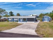 Charming blue single-story home with a well-maintained lawn, long driveway, and storage shed at 832 E 4Th St, Englewood, FL 34223