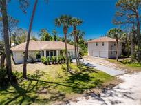 Charming single-story home featuring lush tropical landscaping, palm trees, and a detached garage with a second-story loft at 941 Allen Ave, Englewood, FL 34223