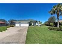 Charming single-story home featuring a well-manicured lawn, three-car garage, and tropical landscaping at 1078 Boundary Blvd, Rotonda West, FL 33947