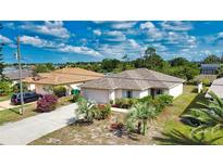A well-maintained home with lush landscaping, an attached two-car garage, and a long driveway at 116 Albatross Rd, Rotonda West, FL 33947