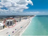 Beautiful beachfront condo building with pristine sandy beach and turquoise waters on a sunny day at 2792 N Beach Rd # 301, Englewood, FL 34223