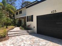 Home exterior featuring a dark garage, stone walkway, and lush landscaping at 425 Laurel W Rd, Nokomis, FL 34275