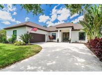Inviting single-story home with a tile roof, arched entryway, manicured lawn, and circular driveway at 5 Saint John Blvd, Englewood, FL 34223