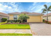 Charming single-story home with well-manicured lawn, palm trees, and a brick paved driveway leading to the garage at 7620 Raptor Ct, North Port, FL 34287
