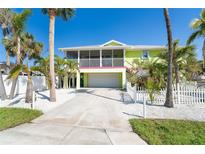 Bright two-story home with a garage, balcony, fenced yard and an abundance of mature tropical palm trees at 130 Sand Dollar Ln, Englewood, FL 34223