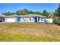 Charming single-story home with a well-maintained lawn and a two-car garage at 2821 Embassy Rd, North Port, FL 34291