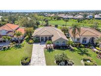 Aerial view of a home with manicured lawn and a paver driveway, surrounded by lush landscaping at 3511 Bay Ridge Way, Port Charlotte, FL 33953
