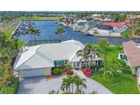 Waterfront home with white tile roof, lush landscaping, and private dock, near the marina and boat slips at 44 Waterford Dr, Englewood, FL 34223
