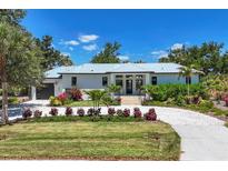 Beautifully landscaped front yard showcasing a modern home with light blue metal roof and circular drive at 4624 Pompano St, Placida, FL 33946
