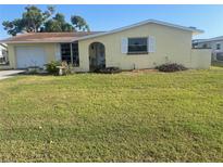 Charming one-story yellow home with a garage and well-maintained front yard at 81 Oakland Hills Pl, Rotonda West, FL 33947