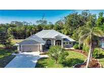Charming home featuring a meticulously manicured lawn, lush tropical landscaping, and a welcoming two-car garage at 941 Elwood Ave, Englewood, FL 34223