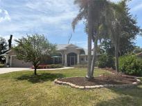 Charming single-story home with manicured lawn, mature trees, and beautiful landscaping at 941 Elwood Ave, Englewood, FL 34223