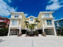 Inviting stilt home with a yellow exterior, palm trees, and ample parking underneath at 1400 Beach Rd # 2, Englewood, FL 34223