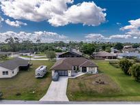 Charming single-story home featuring a well-manicured lawn, RV parking, and a large driveway leading to a two-car garage at 23347 Lehigh Ave, Port Charlotte, FL 33954