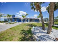 Charming blue single-story home with tropical landscaping, and a sunny driveway at 24805 Nova Ln, Punta Gorda, FL 33980