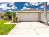Beige two-car garage with an American flag, landscaping, and a spacious concrete driveway on a sunny day at 4207 Fairway Pl, North Port, FL 34287