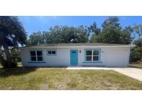 Charming single story home with a new turquoise front door, freshly painted, and nicely manicured lawn at 5417 Postma St, North Port, FL 34287