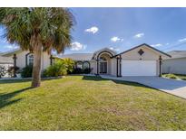 Charming single-story home with lush lawn, mature trees, and a two-car garage at 56 Long Meadow Ct, Rotonda West, FL 33947