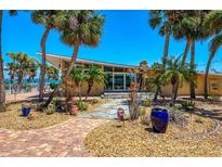 Inviting front exterior with lush landscaping, palm trees, and a unique mid-century modern roofline at 6029 Manasota Key Rd, Englewood, FL 34223