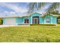 Charming turquoise home featuring a well-manicured lawn and an attached two-car garage at 6062 Spinnaker Blvd, Englewood, FL 34224
