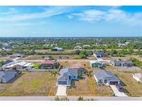 Aerial view of a bright blue one-story home with a grey roof, screened in patio and an attached two-car garage at 12359 Deepwoods Ave, Port Charlotte, FL 33981