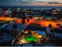 Sunset aerial view of illuminated home with a private pool and close proximity to beach and waterfront at 1245 Gulf Blvd, Englewood, FL 34223