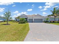 Charming home showcasing a well-maintained lawn, palm trees and a paver driveway at 14556 Gaspar Loop, Port Charlotte, FL 33981