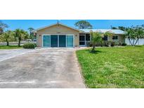 Charming single-story home featuring a well-manicured lawn, metal roof, and a welcoming screened-in porch at 1585 Poinciana Rd, Venice, FL 34293