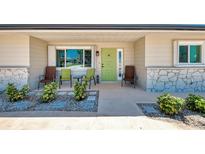 Inviting front porch with seating and a vibrant green door, framed by lush landscaping at 1915 Illinois Ave, Englewood, FL 34224