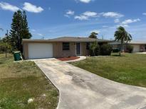 Charming single Gathering home with a one car garage, long driveway, and neatly manicured front lawn under a bright sky at 194 Garden Nw Ave, Port Charlotte, FL 33952
