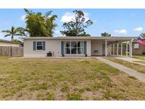 Charming single-story home with blue shutters, a covered carport, and well-maintained landscaping at 21070 Gertrude Ave, Port Charlotte, FL 33952