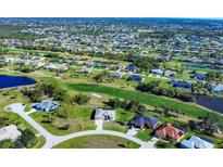 Expansive aerial view of a residential neighborhood with golf course and pond, highlighting community living and lush green spaces at 27 Tee View Rd, Rotonda West, FL 33947