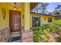 Charming front door with decorative brick accents and a welcoming entryway with lush landscaping at 521 Artists Ave, Englewood, FL 34223