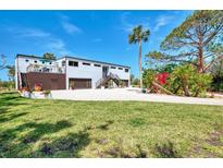 Spacious home with a well-maintained lawn, multiple garage doors, and a beautiful garden at 760 S Oxford Dr, Englewood, FL 34223
