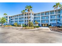 Modern condo building featuring multiple stories, balconies, and tropical landscaping on a sunny day at 8413 Placida Rd # 205, Placida, FL 33946